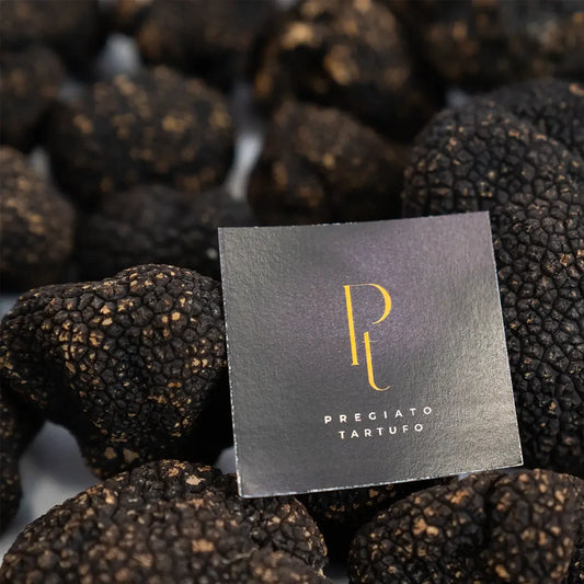 Grupo de trufas negras de verão (Tuber Aestivum) inteiras e limpas, com o logotipo da Pregiato Tartufo. Uma opção mais acessível e aromática para finalizar pratos de massas e saladas. Venda online direta do importador.