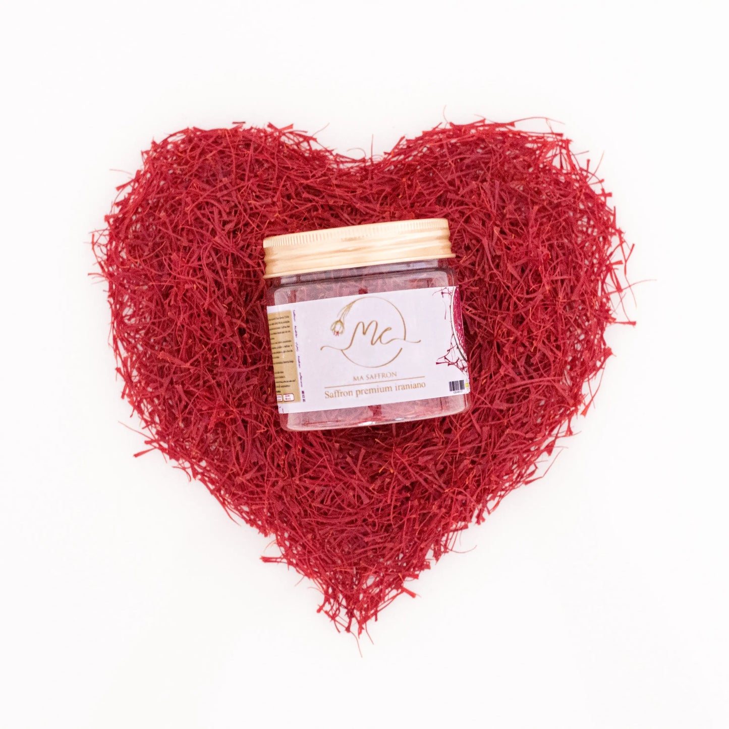 Visão aérea de um pote de açafrão iraniano premium da marca MA Saffron, no centro de uma moldura em formato de coração feita inteiramente com pistilos de açafrão de altíssima qualidade. O coração simboliza a paixão e o amor pelo tempero, destacando a intensidade da cor e o frescor dos estigmas. Esta imagem de luxo e alta gastronomia é perfeita para a divulgação da Pregiato no mercado de trufas e açafrão do Brasil, atraindo chefs e entusiastas gourmet