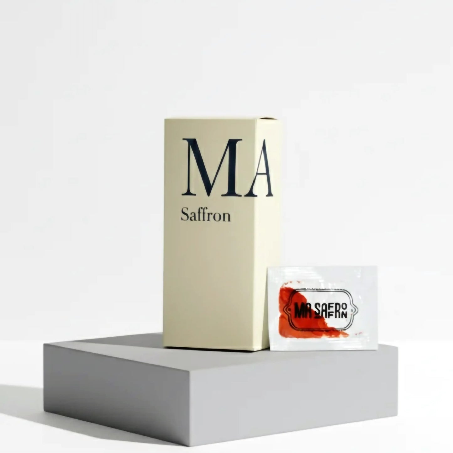 Caixa de produto MA Saffron em fundo claro, com um sachê de açafrão ao lado, destacando a embalagem elegante e o selo de qualidade