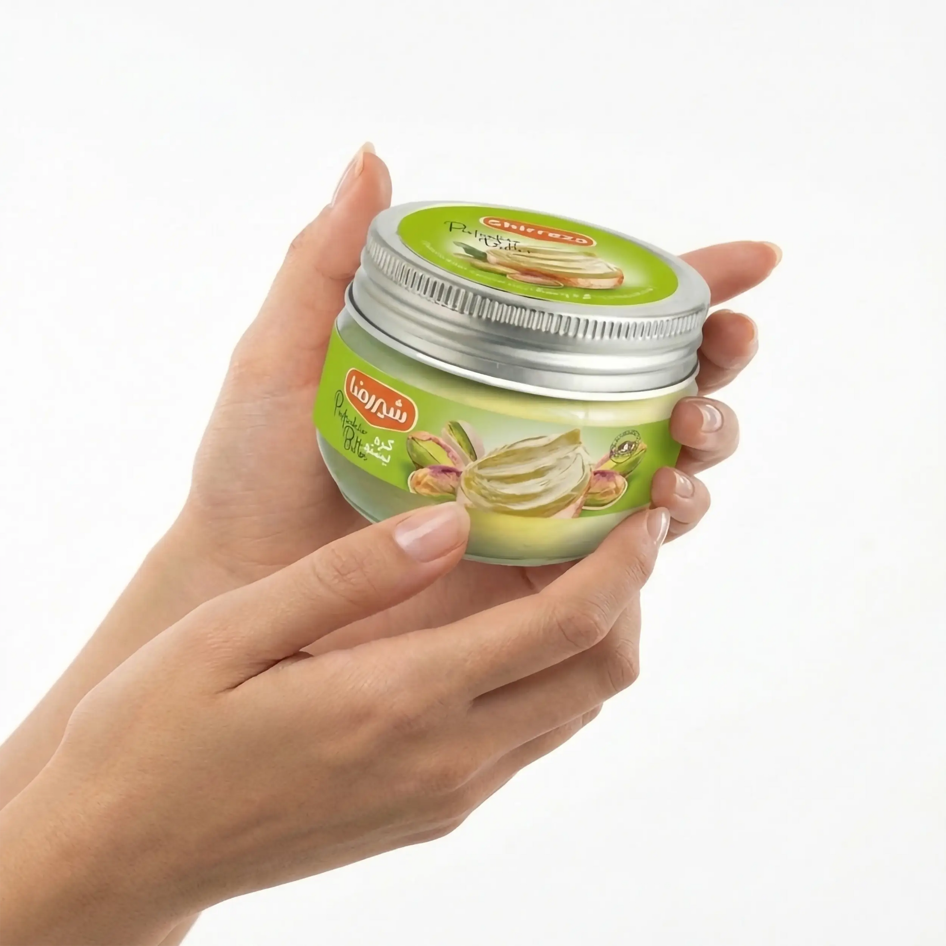 Mãos segurando com cuidado um pote de manteiga de pistache Shirreza. Demonstração do produto premium importado, reconhecido mundialmente pela cremosidade única e sabor autêntico de nozes frescas. Disponível na loja online pregiato tartufo