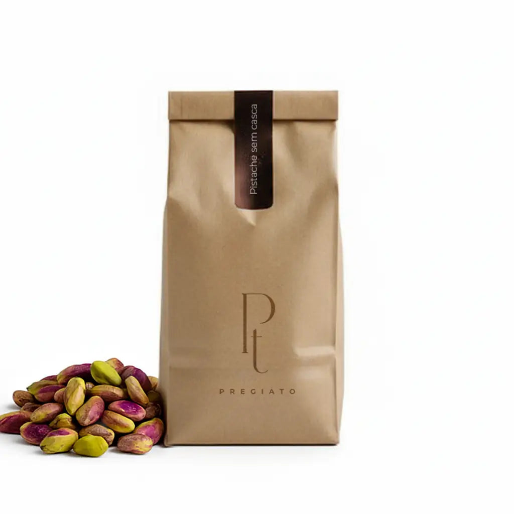 Saco de papel kraft da PREGIATO sobre fundo branco, com um monte de pistaches sem casca ao lado, indicando o conteúdo do produto.